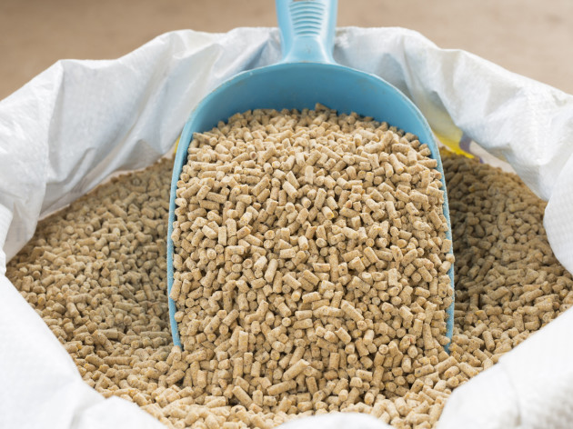 An open sack of animal feed pellets with a scoop on top