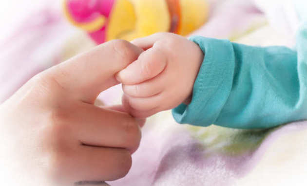 Baby's hand holding an adult's finger