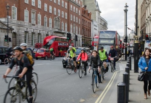Cyclists on their commute in London, on the road with London buses